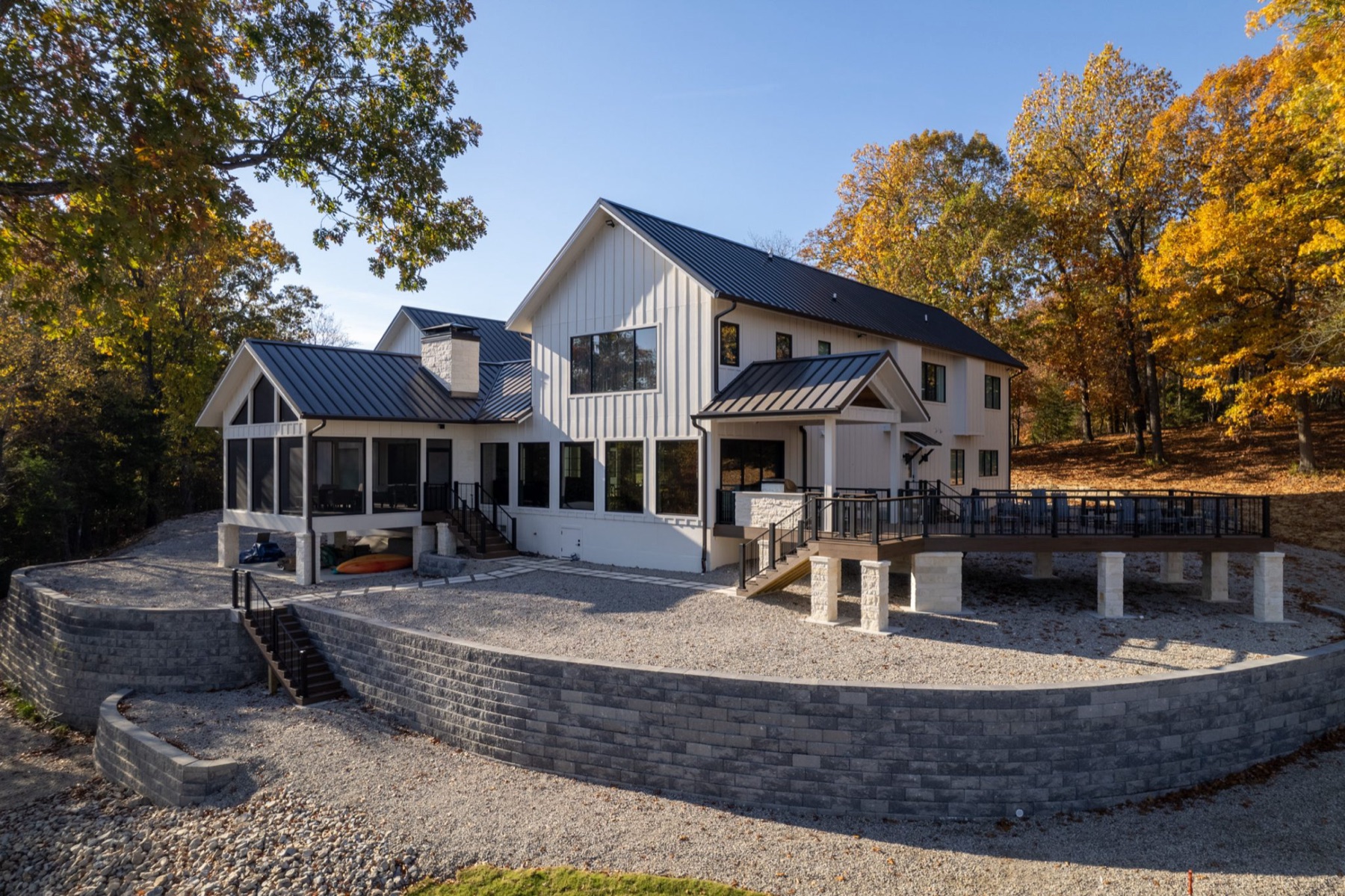 White farmhouse-style custom home on a landscaped hillside