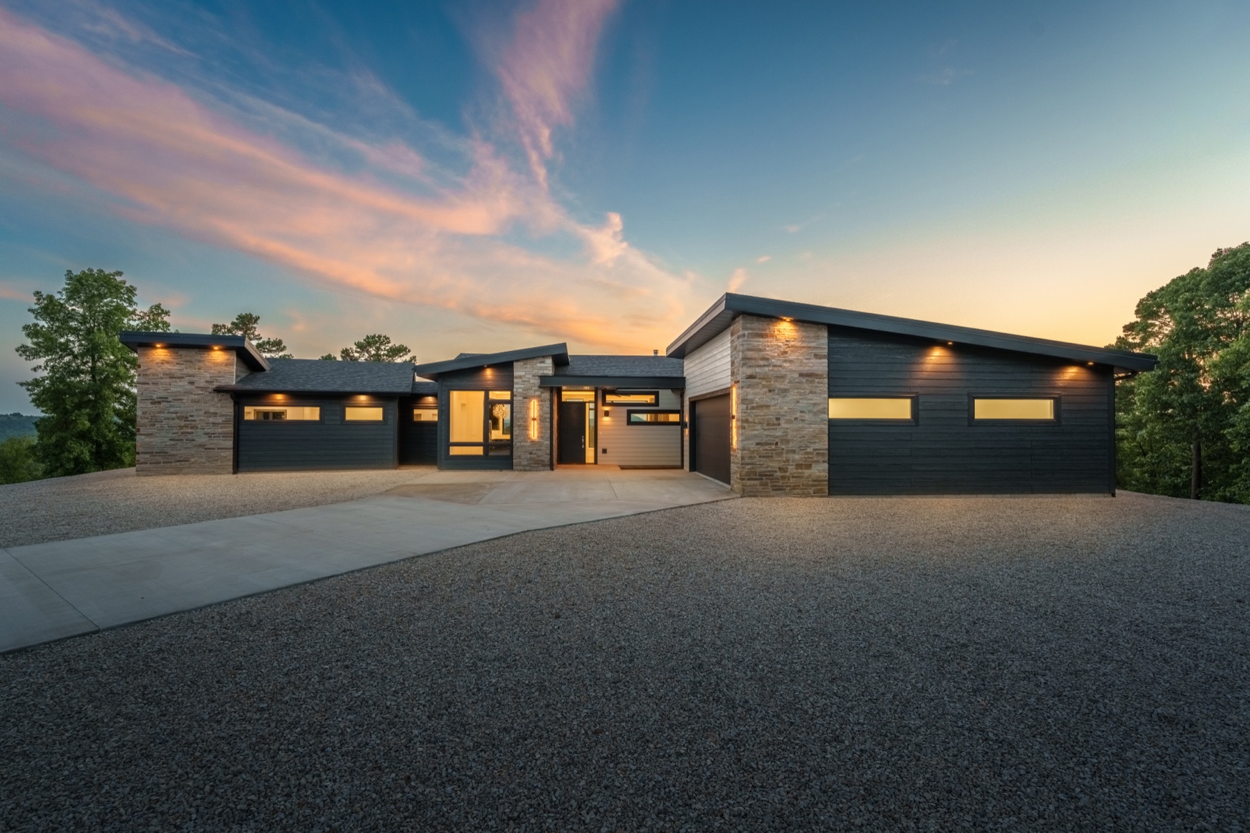 Modern stone and dark-siding custom home at dusk