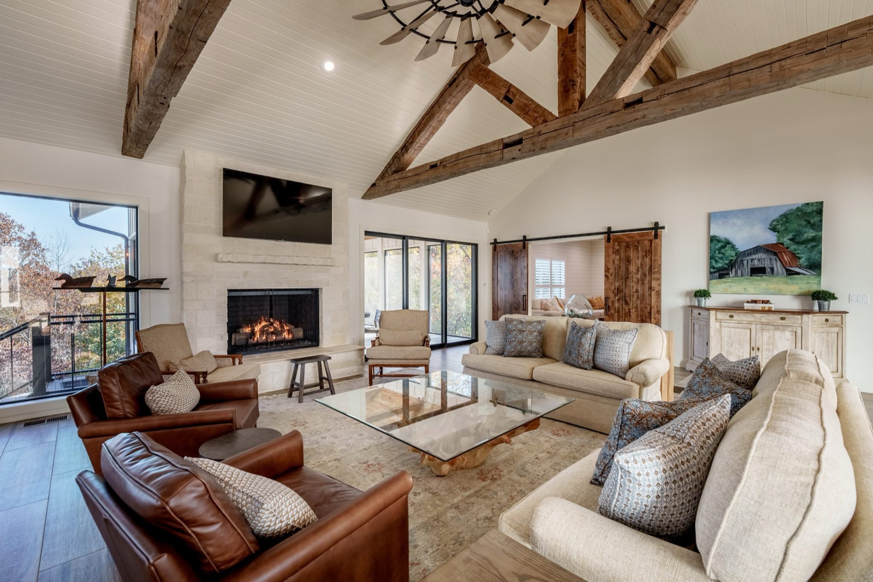 Great room with rustic timber trusses, stone fireplace and leather seating