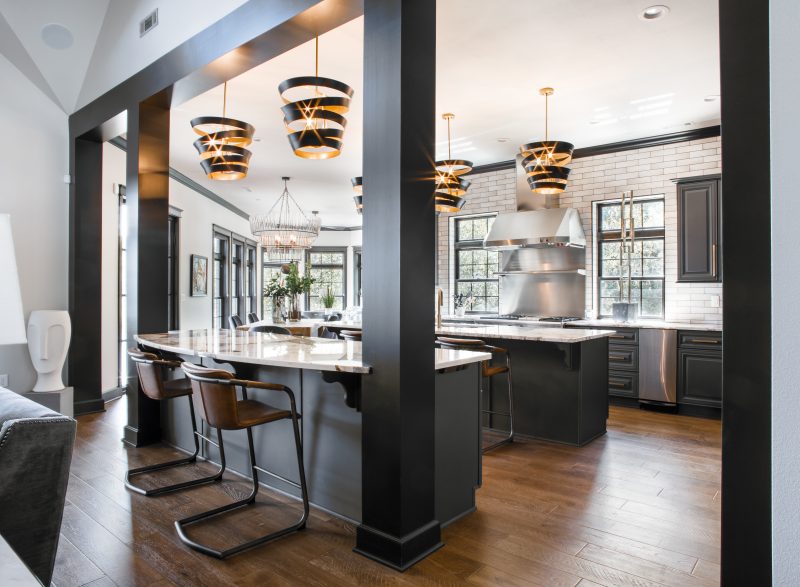 Double-island kitchen with black beams and brass pendant lighting