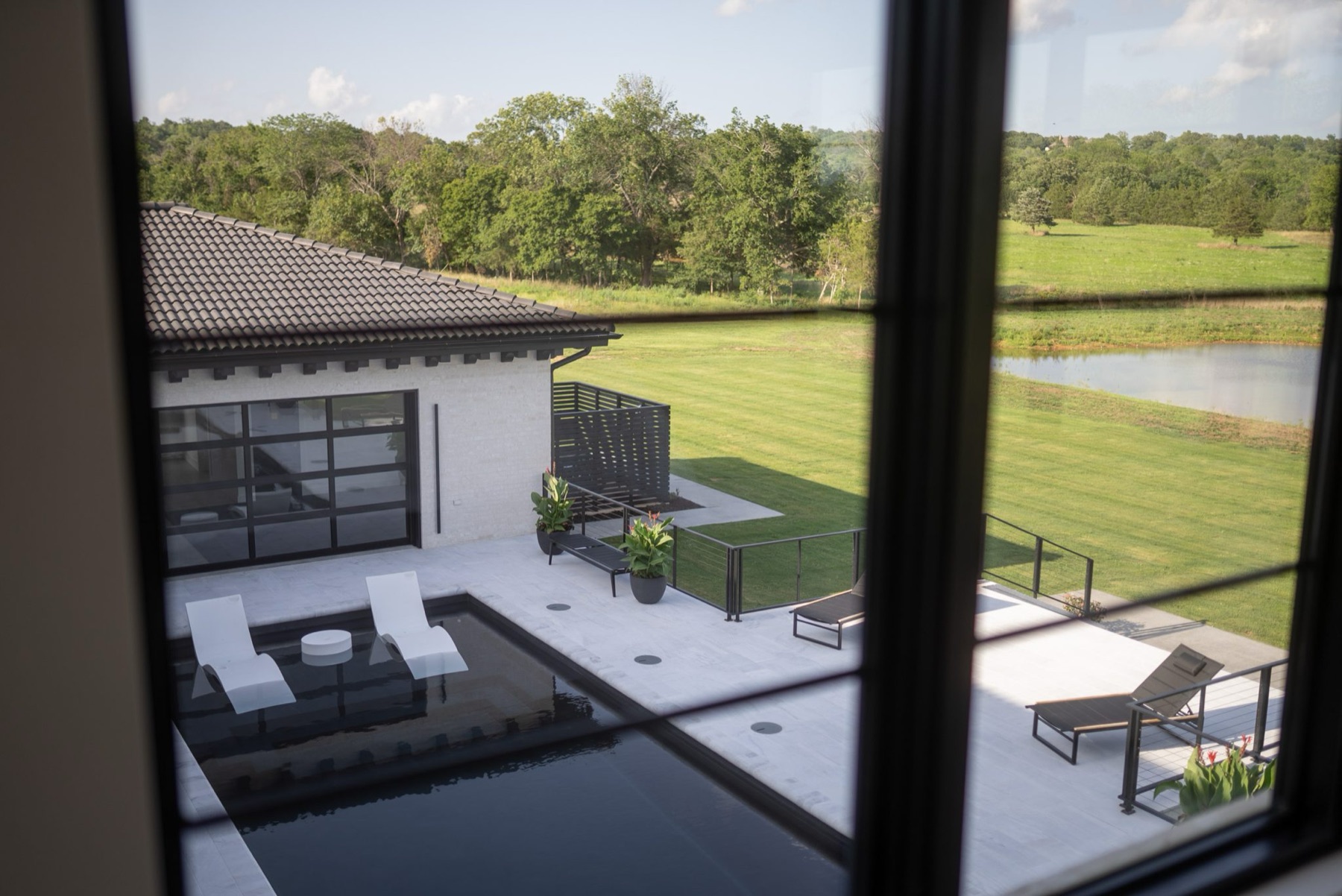View through custom windows onto a backyard pool and patio